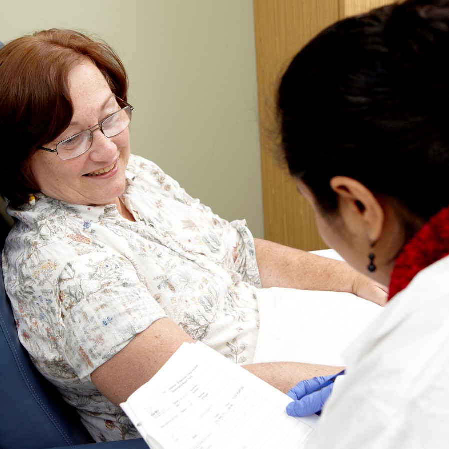 A lab technician speaks to a CLSA participant sitting in a phlebotomy chair.