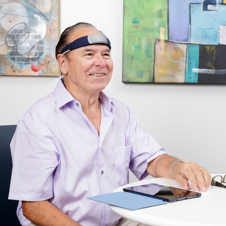 A male CLSA participant smiles while wearing a sleep tracker headband.