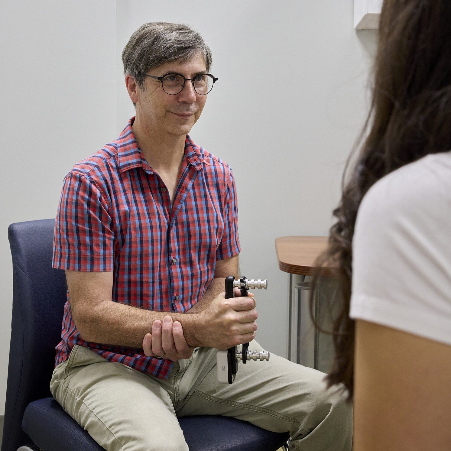 A males CLSA participant smiles at a research assistant while undergoing the grip strength test.